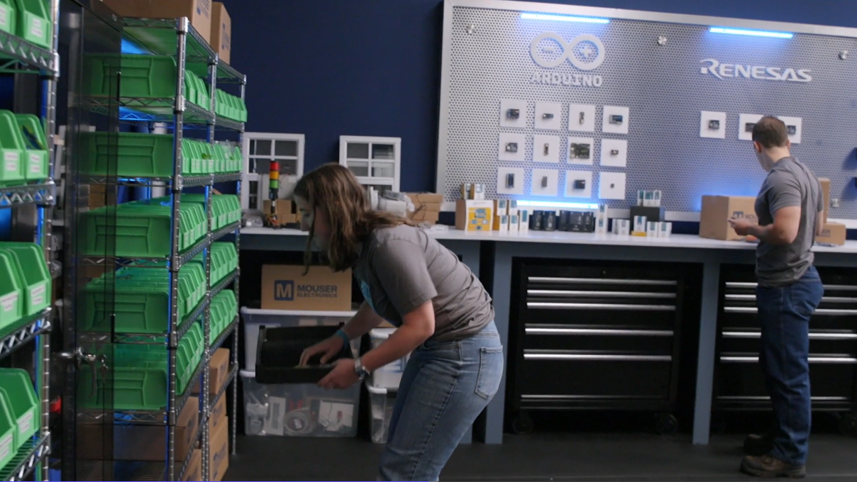 Circuit Showdown scene featuring a student reaching into green bins of electrical components lining a wall